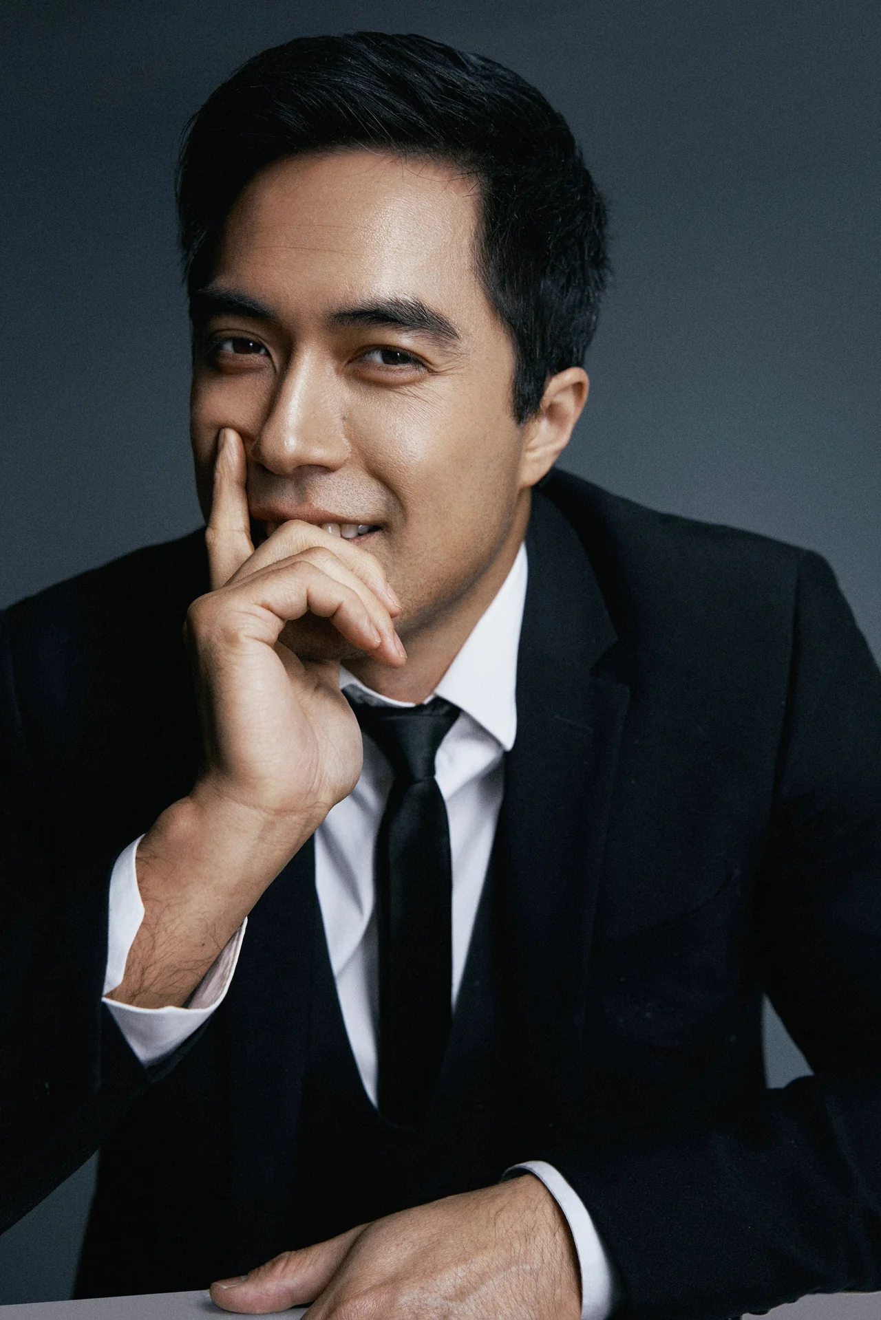 Damien Sato in a tailored suit with a playful expression