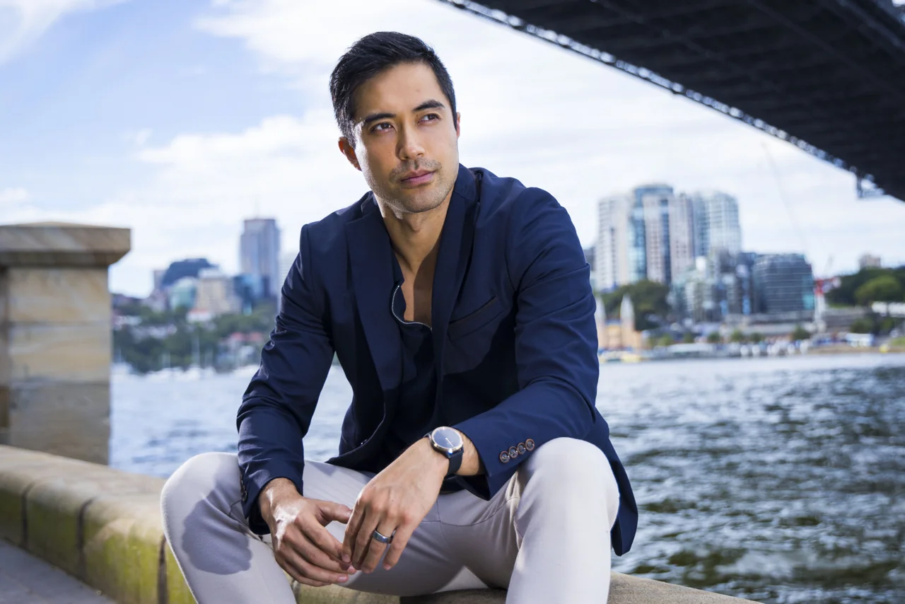 Damien Sato seated by Sydney Harbour