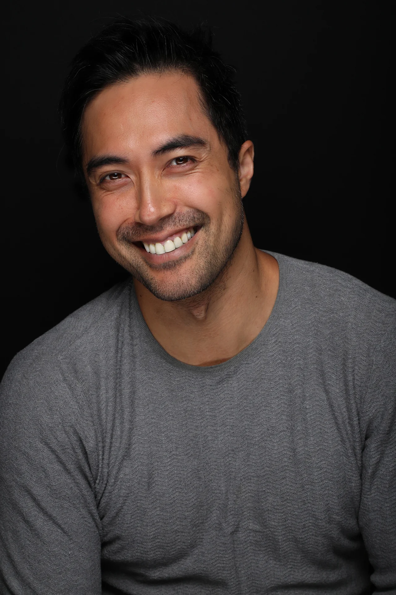 A relaxed, smiling headshot of Damien Sato